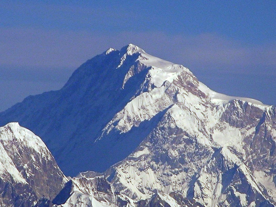 Shishapangma 01 02 Kangchenjunga 01 05 Mountain Flight Shishapangma Close Up Here is a close-up of the summit area of Shishapangma, the 14th highest mountain in the world at 8012m, shining in the early morning sun from Kathmandus Mountain flight. The steep and treacherous southwest face is in shadow on the left. The north face is just visible in the sun on the right. The peak to the right of the sloping long sunny ridge in the middle right is Pungpa Ri (7445m), first climbed in 1982. On the far left below Pungpa Ri with its west face in shadow and the east face fully lit is Nyanang Ri (7071m), called the Rock Tooth.